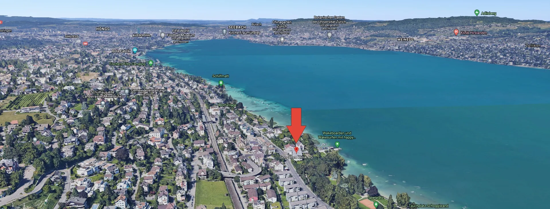 Oblique aerial view from the south: Kilchberg in the foreground with Seegarten Klinik marked, behind it Lake Zurich and the city of Zurich.