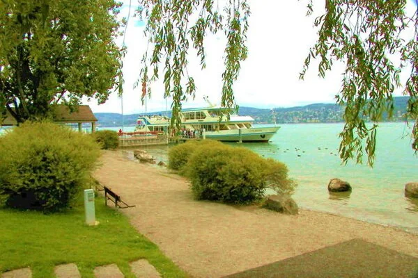 Passenger boat at the Kilchberg-Bendlikon landing stage on Lake Zurich, with the lakeside path in front.